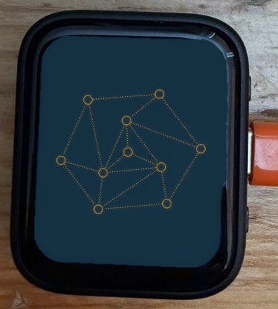 Pan's desk board, close up, an orange cable plugged into its side, showing the thinking face: ten orange rings joined by dotted lines on a dark blue screen
